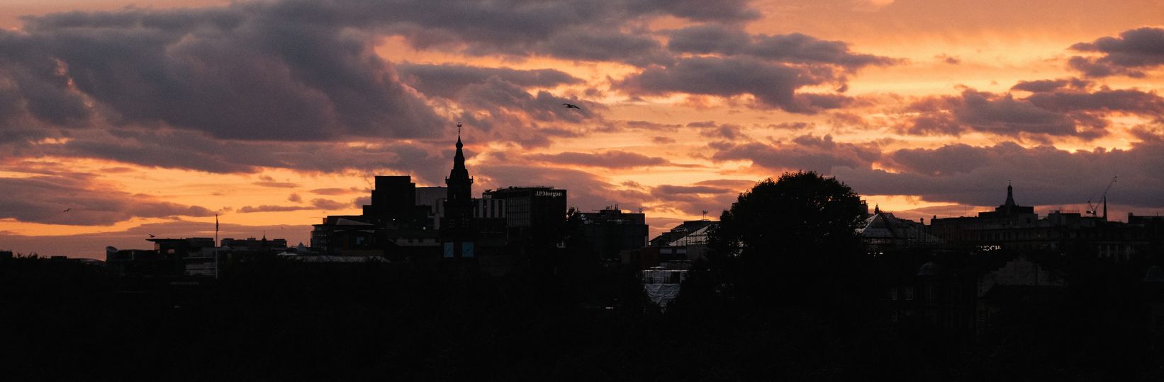 Sunset over glasgow green, the sky is pink with clouds.